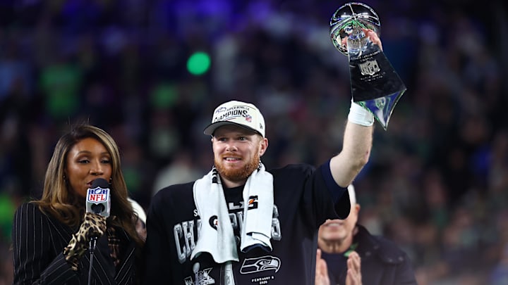 Feb 8, 2026; Santa Clara, CA, USA; Seattle Seahawks quarterback Sam Darnold (14) celebrates with the Vince Lombardi trophy on the podium after defeating the New England Patriots in Super Bowl LX at Levi's Stadium.