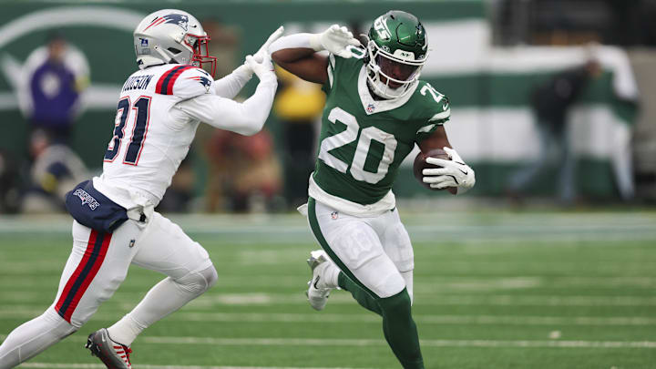 Dec 28, 2025; East Rutherford, New Jersey, USA; New York Jets running back Breece Hall (20) runs the ball against New England Patriots safety Craig Woodson (31) during the second half of the game at MetLife Stadium. Mandatory Credit: Vincent Carchietta-Imagn Images