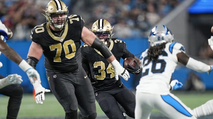Sep 18, 2023; Charlotte, North Carolina, USA; New Orleans Saints running back Tony Jones Jr. (34) follows a block by offensive tackle Trevor Penning (70) against the Carolina Panthers during the second half at Bank of America Stadium. Mandatory Credit: Jim Dedmon-Imagn Images