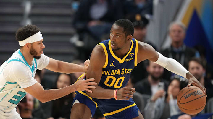 Feb 23, 2024; San Francisco, California, USA; Golden State Warriors forward Jonathan Kuminga (00) handles the ball against Charlotte Hornets guard Seth Curry (left) during the third quarter at Chase Center. Mandatory Credit: Darren Yamashita-Imagn Images