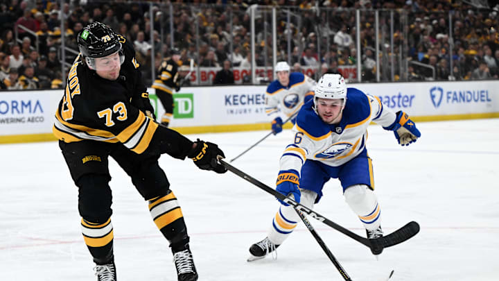 Apr 23, 2026; Boston, Massachusetts, USA; Boston Bruins defenseman Charlie McAvoy (73) clears the puck against Buffalo Sabres left wing Zach Benson (6) during the second period of game three of the first round of the 2026 Stanley Cup Playoffs at the TD Garden. Mandatory Credit: Brian Fluharty-Imagn Images