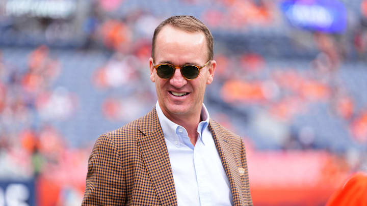 Oct 27, 2024; Denver, Colorado, USA; Retired NFL player Peyton Manning stands on the sidelines of Empower Field at Mile High before the game between the Carolina Panthers Denver Broncos. Mandatory Credit: Ron Chenoy-Imagn Images