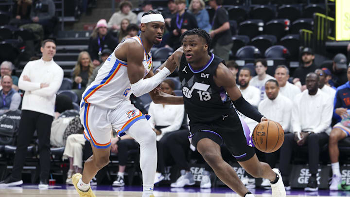Feb 21, 2025; Salt Lake City, Utah, USA; Utah Jazz guard Isaiah Collier (13) drives against Oklahoma City Thunder guard Shai Gilgeous-Alexander (2) during the third quarter at Delta Center. Mandatory Credit: Rob Gray-Imagn Images