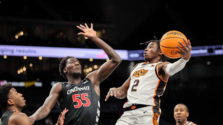Mar 11, 2025; Kansas City, MO, USA; Oklahoma State Cowboys guard Arturo Dean (2) shoots the ball over Cincinnati Bearcats forward Aziz Bandaogo (55) during the first half at T-Mobile Center. Mandatory Credit: William Purnell-Imagn Images