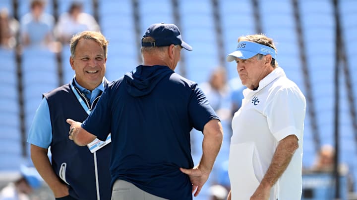 Sep 13, 2025; Chapel Hill, North Carolina, USA; Richmond Spiders head coach Russ Huesman talks to North Carolina Tar Heels general manager Michael Lombardi and head coach Bill Belichick before the game at Kenan Stadium. Sep 13, 2025; Chapel Hill, North Carolina, USA; Richmond Spiders head coach Russ Huesman talks to North Carolina Tar Heels general manager Michael Lombardi and head coach Bill Belichick before the game at Kenan Stadium.