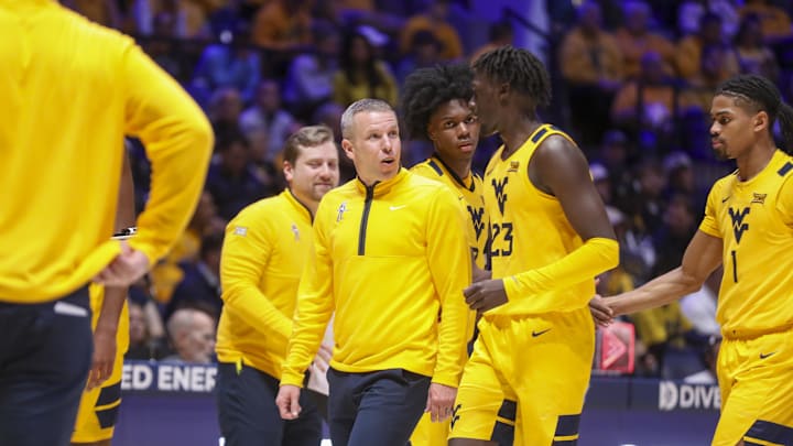 Nov 13, 2025; Morgantown, West Virginia, USA; West Virginia Mountaineers head coach Ross Hodge talks with West Virginia Mountaineers guard Morris Ugusuk (23) during the first half against the Pittsburgh Panthers at WVU Coliseum. Mandatory Credit: Ben Queen-Imagn Images Nov 13, 2025; Morgantown, West Virginia, USA; West Virginia Mountaineers head coach Ross Hodge talks with West Virginia Mountaineers guard Morris Ugusuk (23) during the first half against the Pittsburgh Panthers at WVU Coliseum. Mandatory Credit: Ben Queen-Imagn Images