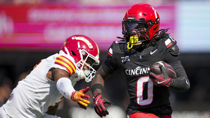 Oct 4, 2025; Cincinnati, Ohio, USA;  Cincinnati Bearcats wide receiver Isaiah Johnson (0) carries the ball against Iowa State Cyclones defensive back Tre Bell (7) in the first half at Nippert Stadium. Mandatory Credit: Aaron Doster-Imagn Images