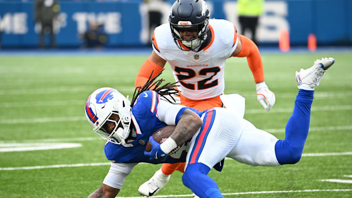Jan 12, 2025; Orchard Park, New York, USA; Buffalo Bills running back James Cook (4) is tackled by Denver Broncos safety Brandon Jones (22) during the second quarter in an AFC wild card game at Highmark Stadium. Mandatory Credit: Mark Konezny-Imagn Images