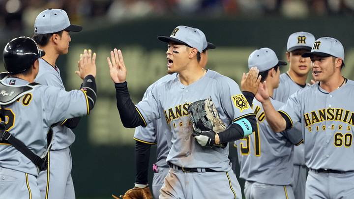Mar 15, 2025; Bunkyo, Tokyo, Japan; Hanshin Tigers right fielder Teruaki Sato (center) celebrates with teammates after defeating the Chicago Cubs at Tokyo Dome. Mandatory Credit: Darren Yamashita-Imagn Images