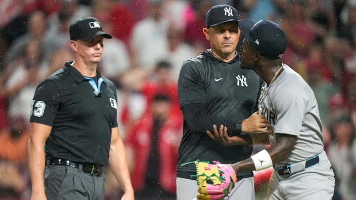 New York Yankees second base Jazz Chisholm Jr. (13) is held back by manager Aaron Boone (17) after being ejected by home plate umpire Mark Wegner (14) in the ninth inning of the MLB interleague game between the Cincinnati Reds and the New York Yankees at Great American Ball Park in downtown Cincinnati on Tuesday, June 24, 2025. The Reds won 5-4 in 11 innings.