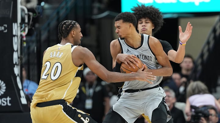 Dec 18, 2025; San Antonio, Texas, USA; San Antonio Spurs forward Victor Wembanyama (1) drives against Washington Wizards forwards Alex Sarr (20) and Kyshawn George (18) during the second half at Frost Bank Center. Mandatory Credit: Scott Wachter-Imagn Images