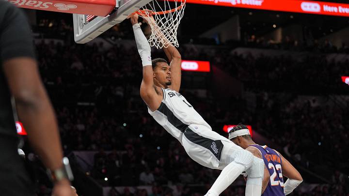 Oct 14, 2026; San Antonio, Texas, USA;  San Antonio Spurs forward Victor Wembanyama (1) hangs on the rim after a dunk in the first half against the Phoenix Suns at Frost Bank Center.  