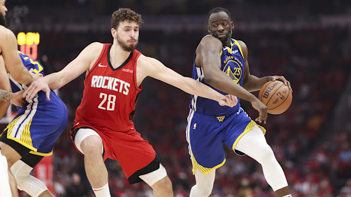 Golden State Warriors forward Draymond Green dribbles the ball as Houston Rockets center Alperen Sengun defends.