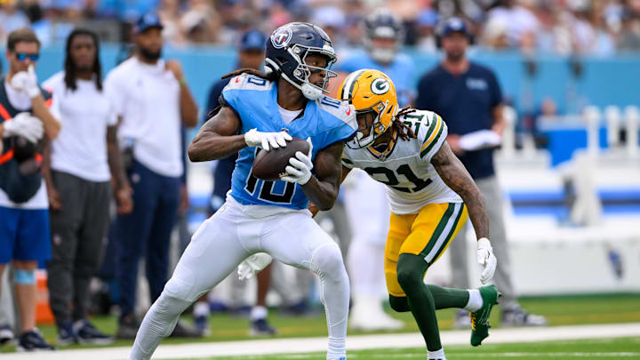 Sep 22, 2024; Nashville, Tennessee, USA;  Tennessee Titans wide receiver DeAndre Hopkins (10) makes a catch as Green Bay Packers cornerback Eric Stokes (21) converses during the first half at Nissan Stadium. Mandatory Credit: Steve Roberts-Imagn Images