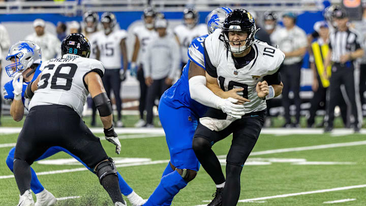 Nov 17, 2024; Detroit, Michigan, USA; Jacksonville Jaguars quarterback Mac Jones (10) passes the ball and is pressured by Detroit Lions defensive end Levi Onwuzurike (91) during the second half at Ford Field. Mandatory Credit: David Reginek-Imagn Images