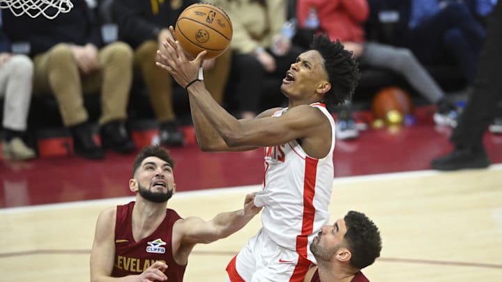 Jan 25, 2025; Cleveland, Ohio, USA; Houston Rockets forward Amen Thompson (1) drives to the basket between Cleveland Cavaliers guard Ty Jerome (2) and forward Georges Niang (20) in the fourth quarter at Rocket Mortgage FieldHouse. Mandatory Credit: David Richard-Imagn Images