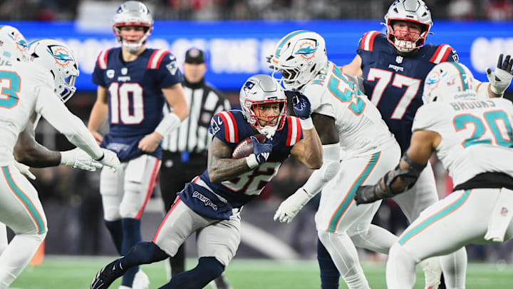 Jan 4, 2026; Foxborough, Massachusetts, USA; New England Patriots running back TreVeyon Henderson (32) runs the ball against Miami Dolphins center Aaron Brewer (55) during the first quarter at Gillette Stadium. Mandatory Credit: Brian Fluharty-Imagn Images Jan 4, 2026; Foxborough, Massachusetts, USA; New England Patriots running back TreVeyon Henderson (32) runs the ball against Miami Dolphins center Aaron Brewer (55) during the first quarter at Gillette Stadium. Mandatory Credit: Brian Fluharty-Imagn Images