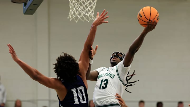 Jacksonville Dolphins guard Robert McCray V (13) drives the lane against North Florida Ospreys forward Josh Harris (10) during the first half of an NCAA men’s basketball matchup Saturday, Feb. 1, 2025 at Jacksonville University in Jacksonville, Fla. [Corey Perrine/Florida Times-Union]