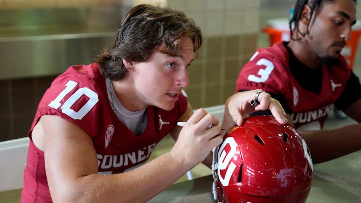 Oklahoma Sooners quarterback John Mateer (10) signs a helmet for a fan during Meet the Sooners Day at Gaylord Family Ñ Oklahoma Memorial Stadium, Saturday, Aug. 2, 2025.