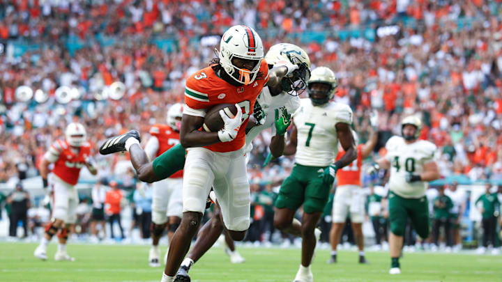 Sep 13, 2025; Miami Gardens, Florida, USA; Miami Hurricanes wide receiver Joshua Moore (3) holds off South Florida Bulls cornerback Ben Knox (1) for a touchdown in the first quarter in the first quarter  at Hard Rock Stadium. Mandatory Credit: Nathan Ray Seebeck-Imagn Images