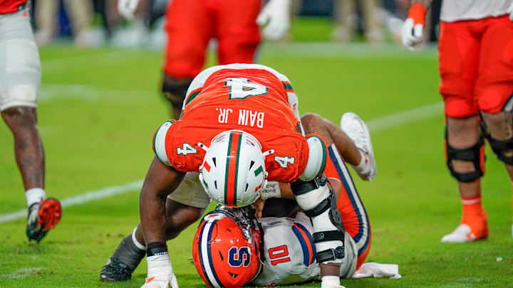 Nov 8, 2025; Miami Gardens, Florida, USA; Syracuse Orange quarterback Rickie Collins (10) is sacked by Miami Hurricanes defensive lineman Rueben Bain Jr. (4) during the fourth quarter at Hard Rock Stadium. Mandatory Credit: Jeff Romance-Imagn Images