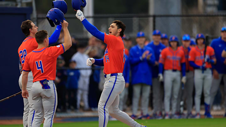 Florida utility Jac Caglianone (14) taps helmets with catcher Luke Heyman (28) and infielder Cade