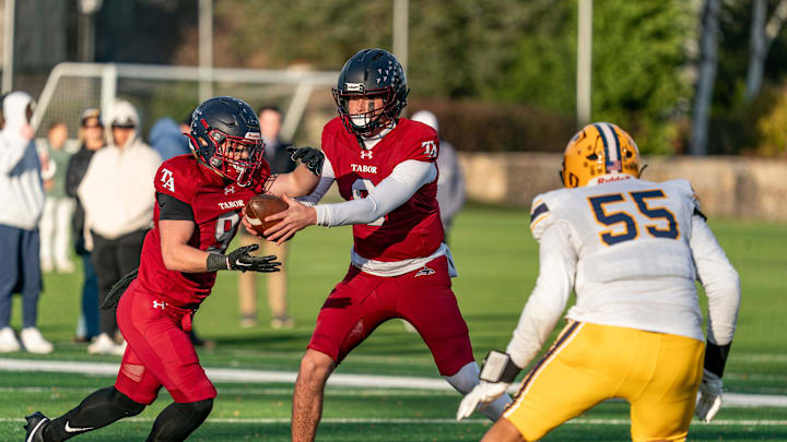 Tabor Academy's quarterback Peter Bourque hands the ball off to Lucas Fickeisen.