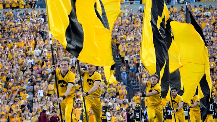 The Iowa Hawkeyes spirit squad runs flags across the field as the players swarm onto the field ahead of the football game against the Massachusetts Minutemen Sept. 13, 2025 at Kinnick Stadium in Iowa City, Iowa.
