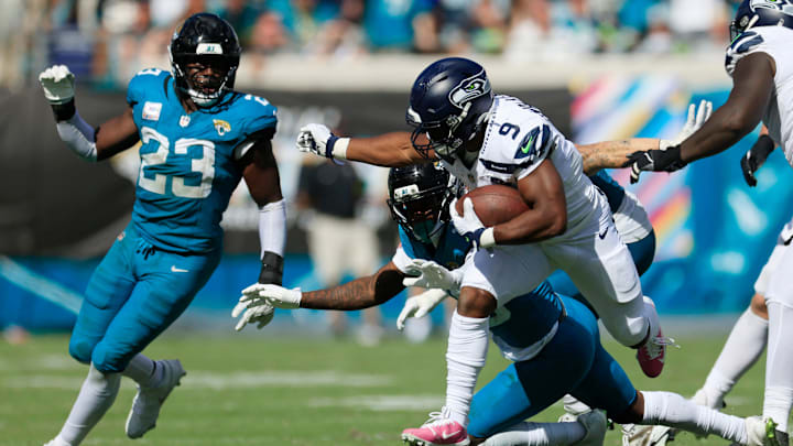 Seattle Seahawks running back Kenneth Walker III (9) rushes for yards as Jacksonville Jaguars cornerback Montaric Brown (30) pressures and linebacker Foye Oluokun (23) looks on during the fourth quarter of an NFL football matchup, Sunday, Oct. 12, 2025, at EverBank Stadium in Jacksonville, Fla. 