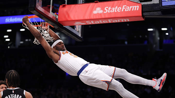 New York Knicks forward Precious Achiuwa hangs on the rim after dunking the ball during the first half. Mandatory Credit: Vincent Carchietta-Imagn Images