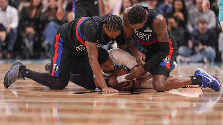 Feb 9, 2026; Charlotte, North Carolina, USA;  Charlotte Hornets forward Brandon Miller (24) tries to hold the ball pressured by Detroit Pistons forward Paul Reed (7) and  guard/forward Ausar Thompson (9) during the second half at Spectrum Center. Mandatory Credit: Jim Dedmon-Imagn Images