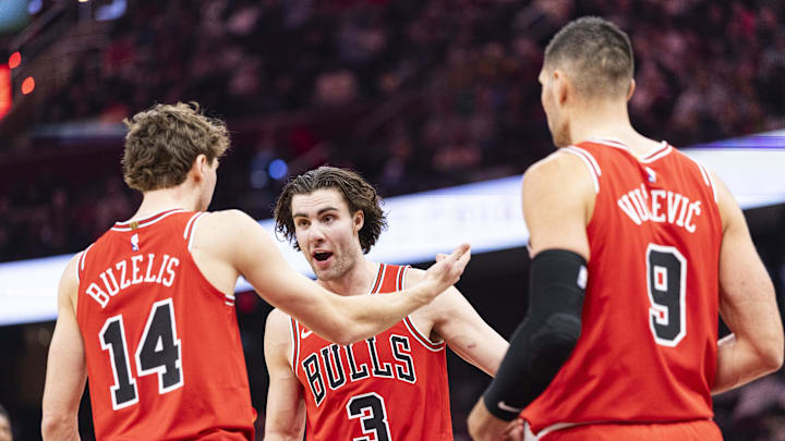 Dec 19, 2025; Cleveland, Ohio, USA; Chicago Bulls guard Josh Giddey (3) talks with forward Matas Buzelis (14) and center Nikola Vučević (9) during a timeout against the Cleveland Cavaliers during the second quarter at Rocket Arena. Mandatory Credit: Scott Galvin-Imagn Images