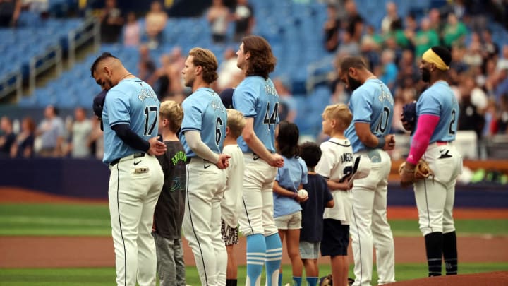 Tampa Bay Rays third base Isaac Paredes (17), shortstop Taylor Walls (6),  pitcher Ryan Pepiot (44), outfielder Amed Rosario (10) and first base Yandy Diaz (2) stand with kids during the national anthem against the Cleveland Guardians on July 14.