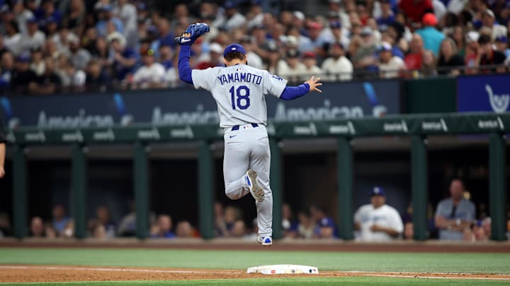 Arlington, Texas, USA; Los Angeles Dodgers pitcher Yoshinobu Yamamoto (18) makes a putout during the third inning against the Texas Rangers at Globe Life Field. Arlington, Texas, USA; Los Angeles Dodgers pitcher Yoshinobu Yamamoto (18) makes a putout during the third inning against the Texas Rangers at Globe Life Field.