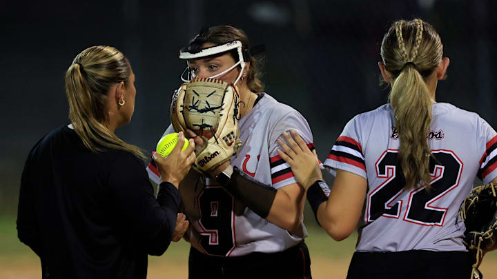 Middleburg's Lily Bennett (9) relieves Karleigh Sanford (22) as head coach Ashley Houston talks with Bennett during the sixth inning of a high school softball matchup at Baldwin Middle-Senior High School Tuesday, April 22, 2025 in Baldwin, Fla. Baldwin defeated Middleburg 5-3.