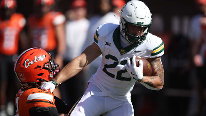 Sep 27, 2025; Stillwater, Oklahoma, USA; Baylor Bears running back Caden Knighten (22) breaks a tackle by Oklahoma State Cowboys safety Dylan Smith (11) during the first half at Boone Pickens Stadium. Mandatory Credit: William Purnell-Imagn Images