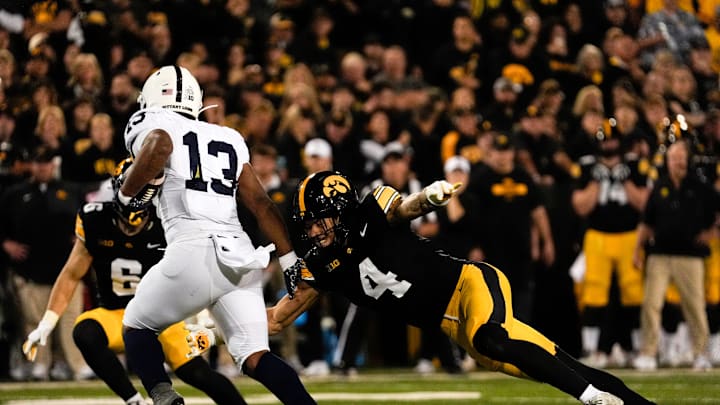 Iowa Hawkeyes defensive back Koen Entringer (4) reaches for Penn State Nittany Lions running back Kaytron Allen (13) during a college football game Oct. 18, 2025 at Kinnick Stadium in Iowa City, Iowa.