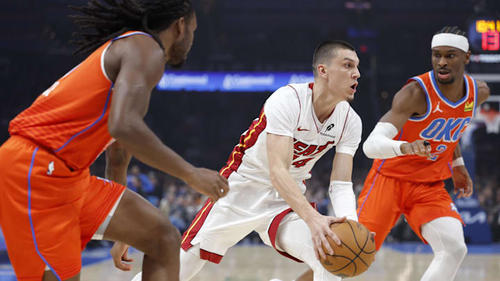 Jan 11, 2026; Oklahoma City, Oklahoma, USA; Miami Heat guard Tyler Herro (14) drives between Oklahoma City Thunder guard Cason Wallace (22) and guard Shai Gilgeous-Alexander (2) during the first quarter at Paycom Center. Mandatory Credit: Alonzo Adams-Imagn Images