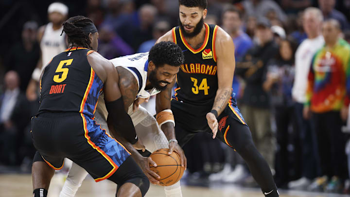 Nov 17, 2024; Oklahoma City, Oklahoma, USA; Dallas Mavericks guard Kyrie Irving (11) moves the ball between Oklahoma City Thunder guard Luguentz Dort (5) and forward Kenrich Williams (34) during the second half at Paycom Center. Mandatory Credit: Alonzo Adams-Imagn Images Nov 17, 2024; Oklahoma City, Oklahoma, USA; Dallas Mavericks guard Kyrie Irving (11) moves the ball between Oklahoma City Thunder guard Luguentz Dort (5) and forward Kenrich Williams (34) during the second half at Paycom Center. Mandatory Credit: Alonzo Adams-Imagn Images