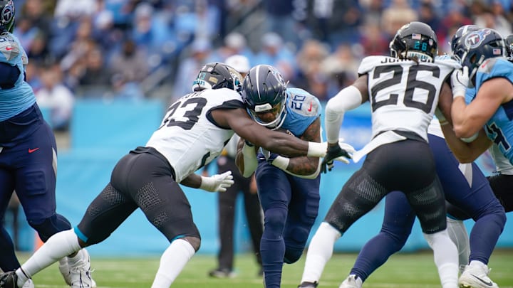 Tennessee Titans running back Tony Pollard (20) is stopped by Jacksonville Jaguars linebacker Devin Lloyd (33) during the first quarter at Nissan Stadium in Nashville, Tenn., Sunday, Dec. 8, 2024.