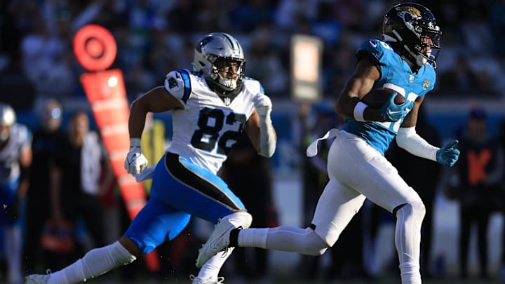 Jacksonville Jaguars safety Antonio Johnson (26) rushes for yards after catching an interception as Carolina Panthers tight end Tommy Tremble (82) chases during the fourth quarter of a regular season NFL football matchup Sunday, Dec. 31, 2023 at EverBank Stadium in Jacksonville, Fla. The Jacksonville Jaguars blanked the Carolina Panthers 26-0. [Corey Perrine/Florida Times-Union]