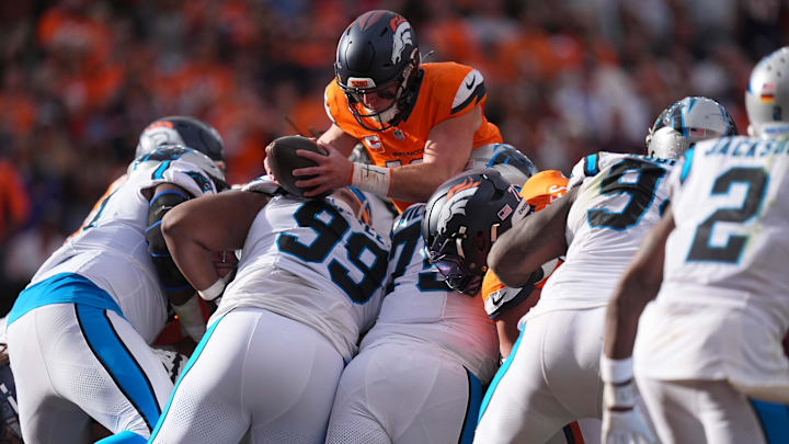 Oct 27, 2024; Denver, Colorado, USA; Denver Broncos quarterback Bo Nix (10) leaps to score a touchdown over Carolina Panthers defensive tackle Shy Tuttle (99) and in the second quarter at Empower Field at Mile High. 