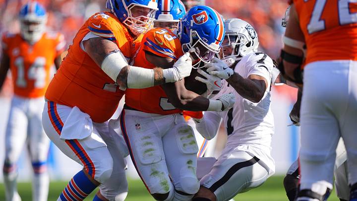 Oct 6, 2024; Denver, Colorado, USA; Las Vegas Raiders safety Tre'von Moehrig (7) hangs onto Denver Broncos running back Javonte Williams (33) as guard Ben Powers (74) in the second half at Empower Field at Mile High. Mandatory Credit: Ron Chenoy-Imagn Images