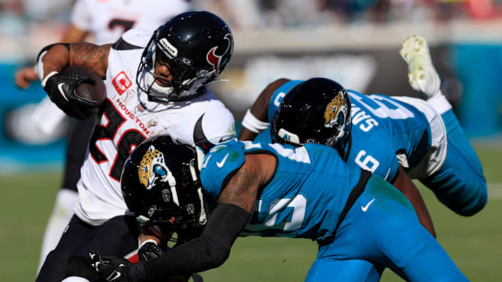 Houston Texans running back Joe Mixon (28), left, is tackled by Jacksonville Jaguars safety Antonio Johnson (26) and safety Darnell Savage (6), back, during the second quarter of an NFL football matchup Sunday, Dec. 1, 2024 at EverBank Stadium in Jacksonville, Fla. [Corey Perrine/Florida Times-Union]