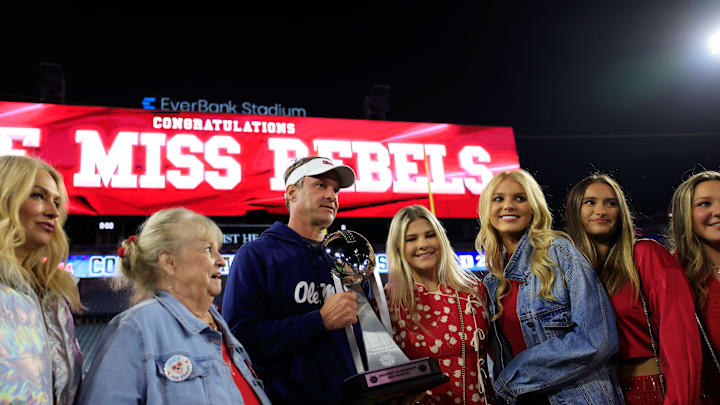 Mississippi Rebels head coach Lane Kiffin, center left, poses with the Ash Verlander Champions Trophy with his family after the game of the TaxSlayer Gator Bowl.