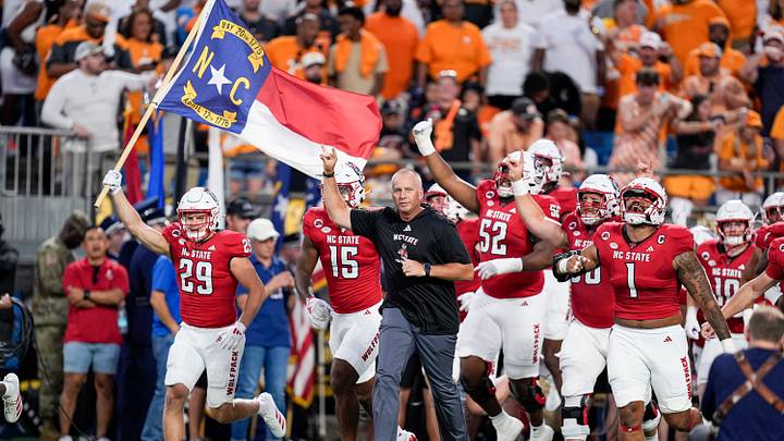 Sep 7, 2024; Charlotte, North Carolina, USA; North Carolina State Wolfpack head coach Dave Doeren leads his team onto the field against the Tennessee Volunteers during the first quarter at the Dukes Mayo Classic at Bank of America Stadium. Mandatory Credit: Jim Dedmon-Imagn Images Sep 7, 2024; Charlotte, North Carolina, USA; North Carolina State Wolfpack head coach Dave Doeren leads his team onto the field against the Tennessee Volunteers during the first quarter at the Dukes Mayo Classic at Bank of America Stadium. Mandatory Credit: Jim Dedmon-Imagn Images