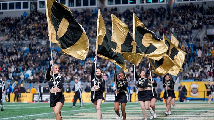 Jan 2, 2026; Charlotte, NC, USA; Wake Forest Demon Deacons cheerleaders run school flags across the end zone after a touchdown against the Mississippi State Bulldogs during the second half at Bank of America Stadium. Mandatory Credit: Jim Dedmon-Imagn Images