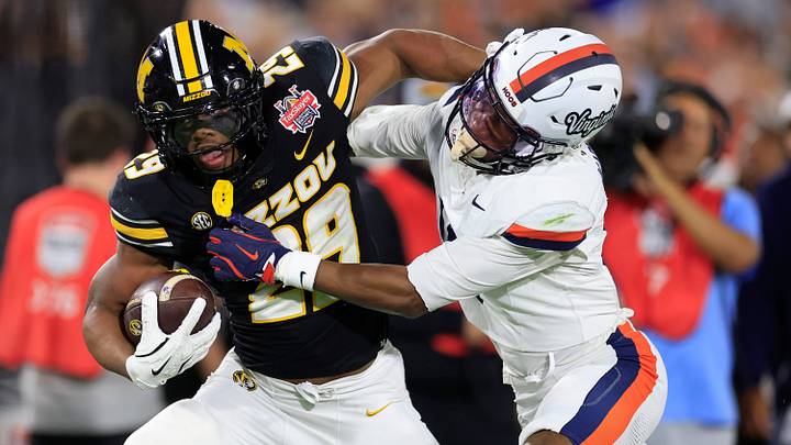 Missouri Tigers running back Ahmad Hardy (29) fends off Virginia Cavaliers cornerback Emmanuel Karnley (19) during the first quarter of the TaxSlayer Gator Bowl at EverBank Stadium, Saturday, Dec. 27, 2025, in Jacksonville. Fla. [Corey Perrine/Florida Times-Union]