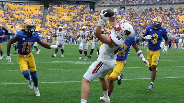 Sep 27, 2025; Pittsburgh, Pennsylvania, USA;  Louisville Cardinals tight end Nate Kurisky (85) catches a touchdown pass behind Pittsburgh Panthers defensive backs Rashad Battle (15) and Cruce Brookins (12) during the fourth quarter at Acrisure Stadium. Mandatory Credit: Charles LeClaire-Imagn Images