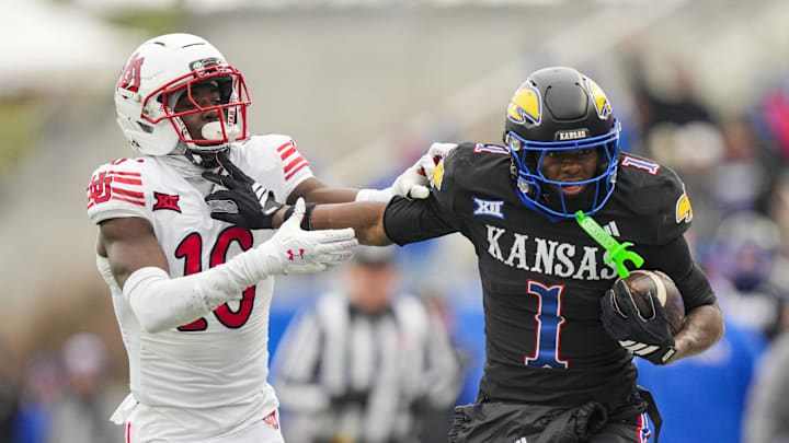 Nov 28, 2025; Lawrence, Kansas, USA; Kansas Jayhawks wide receiver Emmanuel Henderson Jr. (1) runs with the ball against Utah Utes cornerback Blake Cotton (16) during the second half at David Booth Kansas Memorial Stadium. Mandatory Credit: Jay Biggerstaff-Imagn Images